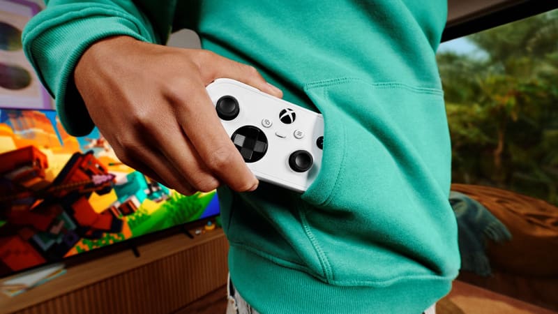 A person holding the compact white Xbox Nano Controller